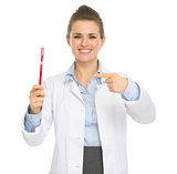 Smiling dental doctor woman pointing toothbrush