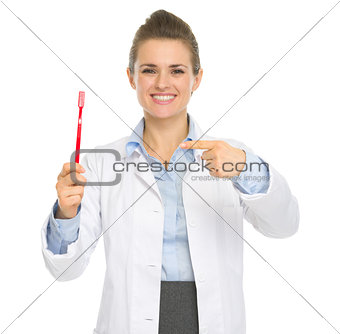 Smiling dental doctor woman pointing toothbrush