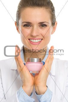 Happy cosmetologist woman showing creme