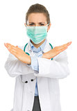 Concerned medical doctor woman in mask showing stop gesture