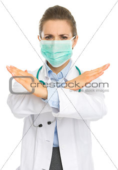Concerned medical doctor woman in mask showing stop gesture