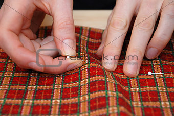 Closeup of two hands pinning red plaid fabric