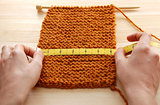 Two hands measuring knitting in inches
