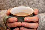 Two hands keeping warm, holding a hot cup of tea or coffee