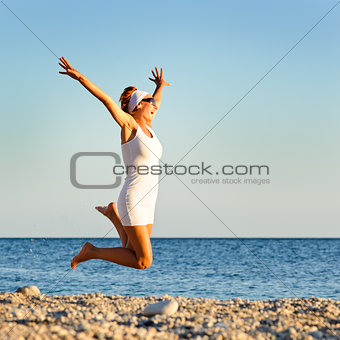 happy young woman is jumping in the beach 
