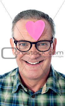 Handsome senior man with paper heart on his forehead