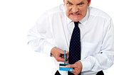 Frustrated businessman cutting his credit card
