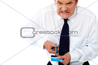 Frustrated businessman cutting his credit card