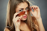 Woman holding sunglasses and looking at you