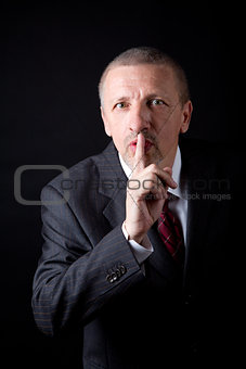 Mature businessman showing hush gesture
