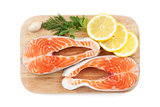 Salmon steaks with herbs and lemon slices on cutting board