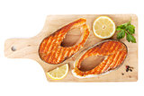 Grilled salmon with lemon slices and herbs on cutting board