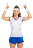 Happy female tennis player pointing up on copy space