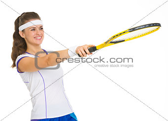 Smiling female tennis player pointing with racket on copy space