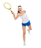 Full length portrait of female tennis player hitting ball