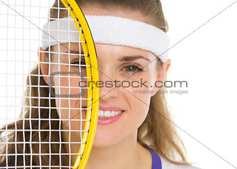 Portrait of female tennis player with racket in front of face