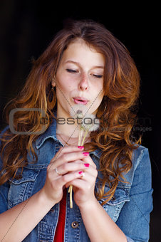 girl blowing on two dandelions