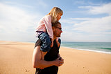 Father carrying daughter on shoulders at the beach