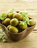 green marinated olives with oregano on a wooden background