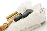 Spa setting with massage stones, brush, flower and a towel