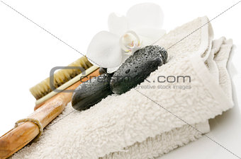 Spa setting with massage stones, brush, flower and a towel