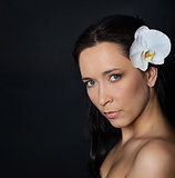 brunette woman with white orchid on black
