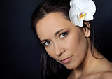 brunette woman with white orchid over black