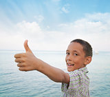 boy showing thumbs-up against sea