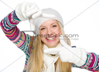 Smiling girl in winter clothes framing with hands