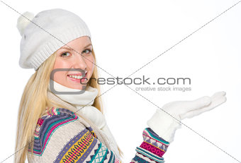 Happy girl in winter clothes presenting something on empty palm