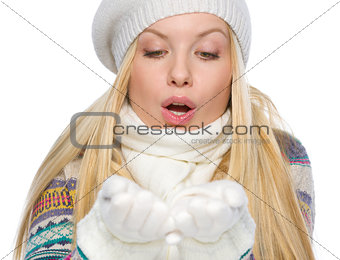 Girl in winter clothes blowing snow