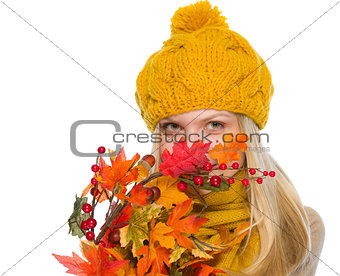 Girl in hat and scarf hiding behind autumn bouquet