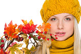 Portrait of girl in hat and scarf holding autumn bouquet