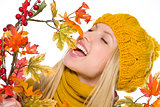 Happy girl in hat and scarf playing with autumn bouquet