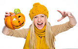 Girl in hat and scarf scaring with jack-o-lantern