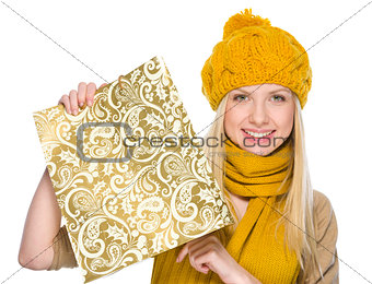 Smiling girl in autumn clothes showing shopping bag