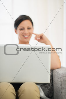 Closeup on laptop and happy young woman in background
