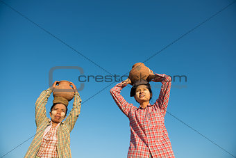 Asian traditional farmers carrying pot on head