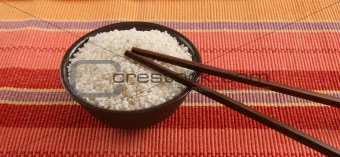 Raw rice in a bowl with sticks
