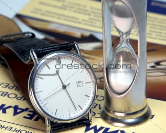 Hourglass and watch on the book on management of time