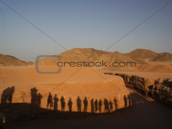 Shadows of tourists on a wall in desert
