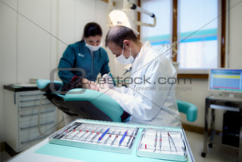Close-up of dentist tools in clinic with patient lying on couch