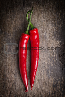 pair of red chili peppers on old wooden table