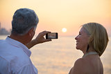 Senior man and woman using mobile phone to take photo