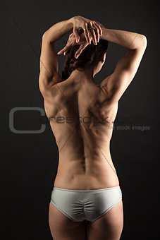Rear view of young fitness woman over black