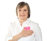 Mature woman holding her paper heart close to body