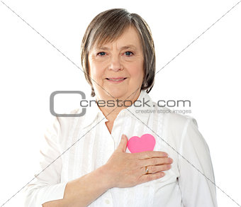 Mature woman holding her paper heart close to body