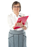 Matured professional woman writing on a red folder