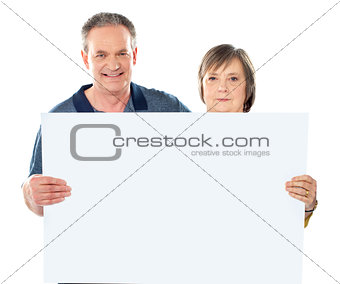 Smiling aged couple displaying blank banner