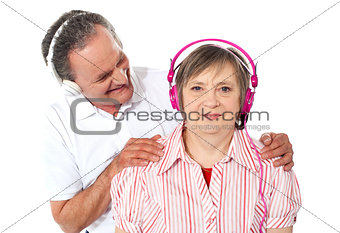 Aged couple enjoying music over white background